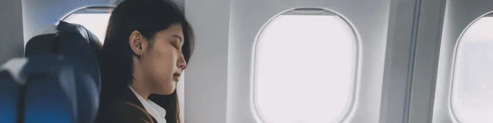 Photo of woman sitting on an airplane trying to sleep